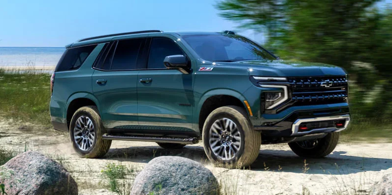 A green 2025 Chevrolet Tahoe parked on the beach.