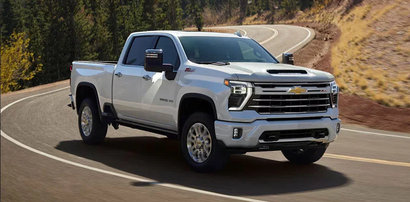 A white Chevrolet Silverado HD driving down the road