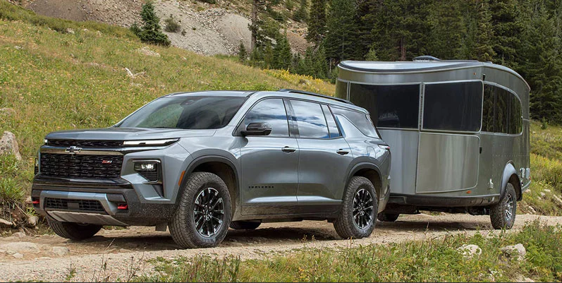 A silver 2026 Chevy Traverse towing a trailer.