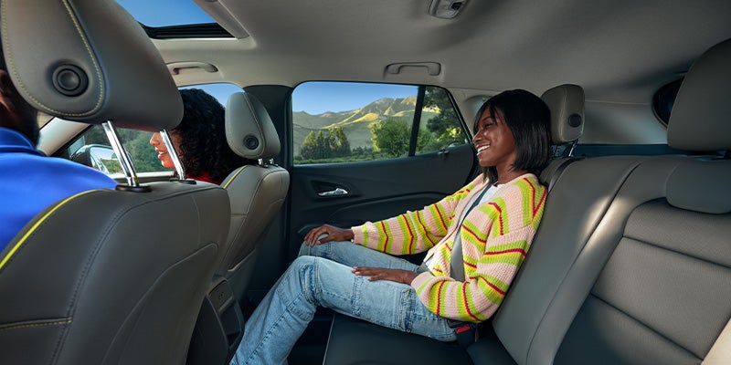 A young teenager sitting in the backseat of the 2025 Chevy Trax.